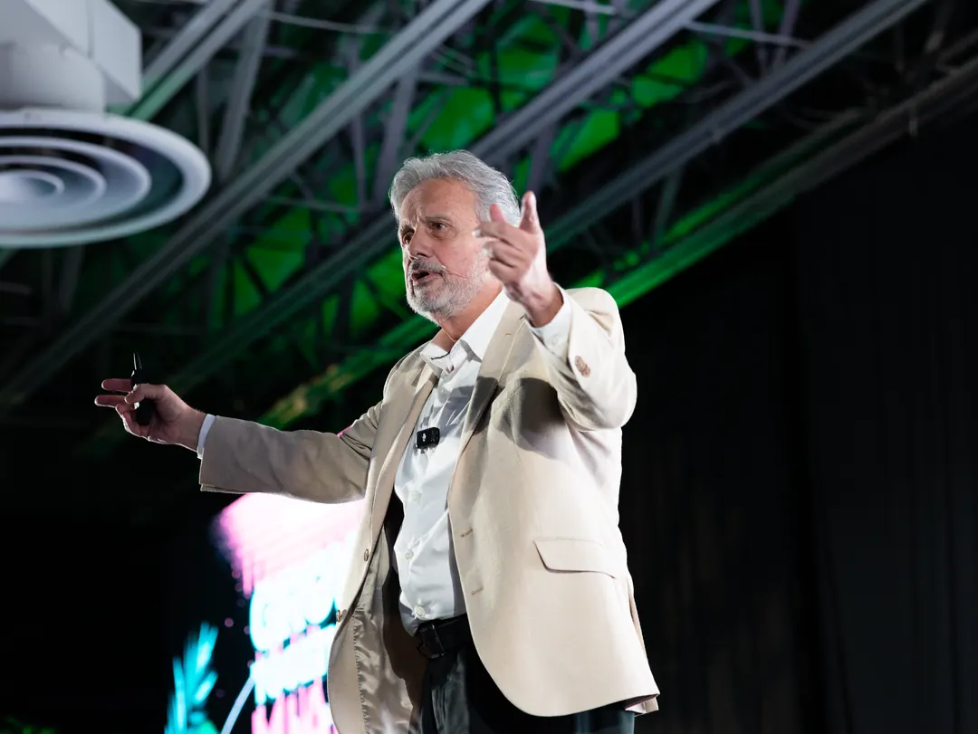 Eduardo Martí en un escenario con luz verde, hablando con un gesto amplio