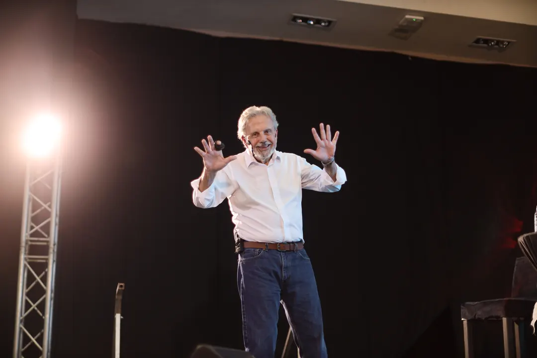 Eduardo Martí sobre un escenario, con las manos abiertas mientras conversa con el público